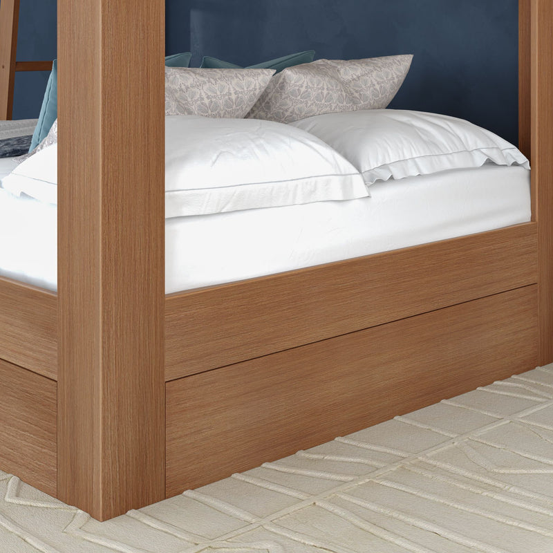 Modern oak four-poster platform bed with crisp white linens, patterned pillows and teal accent cushions on a textured beige rug