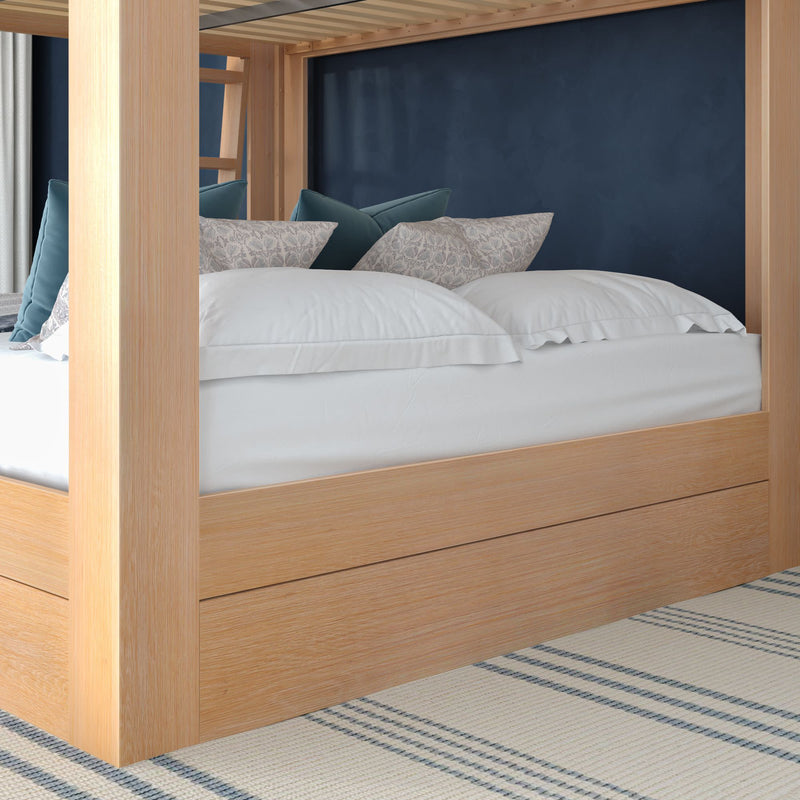 Light oak four-poster canopy bed with white bedding and blue accent pillows against a navy wall in a modern cozy bedroom