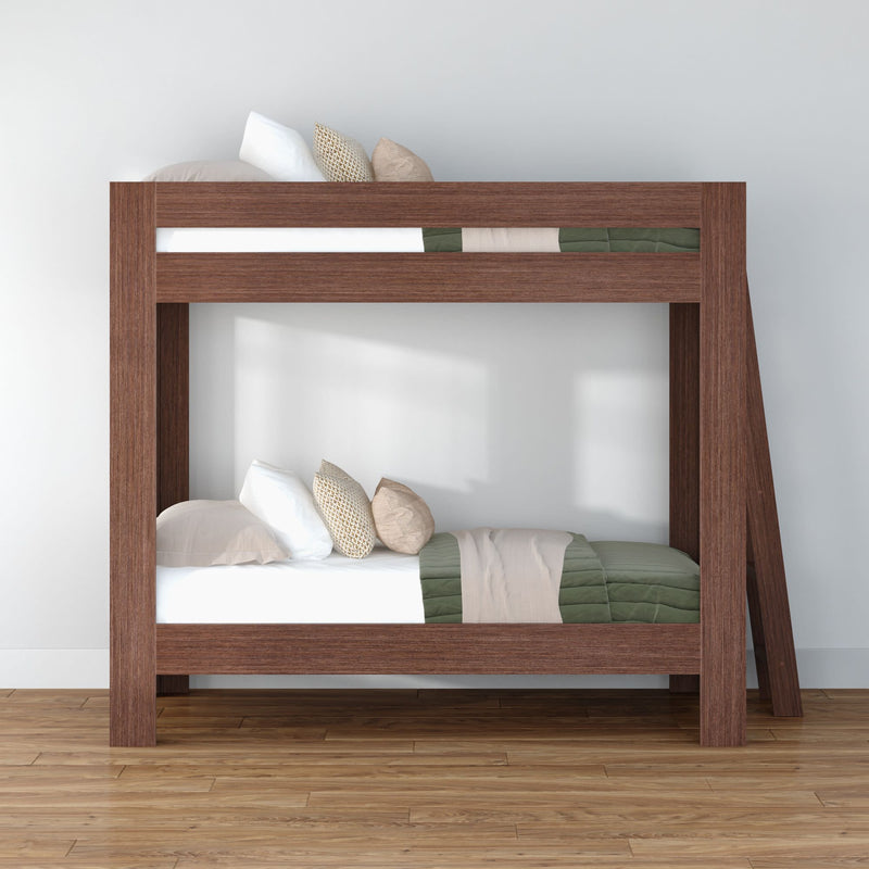Modern solid wood twin-over-twin bunk bed with angled ladder, green and beige bedding and pillows on hardwood floor