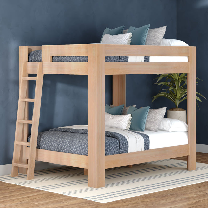 Light wood bunk bed with ladder, blue patterned bedding and teal accent pillows against a navy wall, potted plant and striped rug