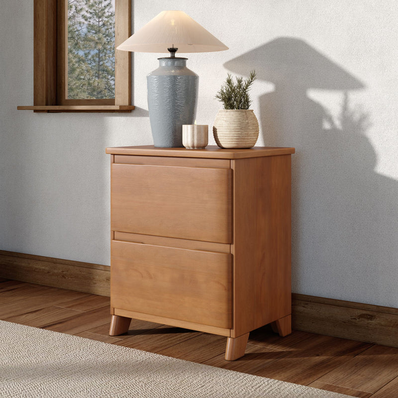Minimalist wooden nightstand with gray ceramic table lamp, ribbed stone vase and small potted green plant beside a window, warm natural light and lamp shadow on neutral wall