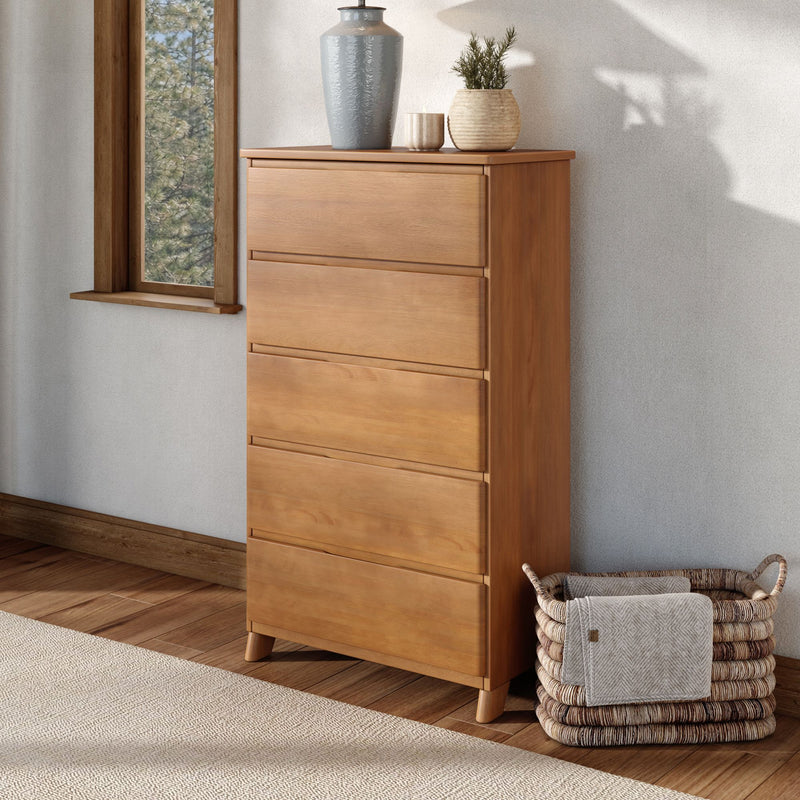 Natural oak dresser with tapered legs, decorative ceramic vases and woven basket in a Scandinavian bedroom by a window with soft natural light