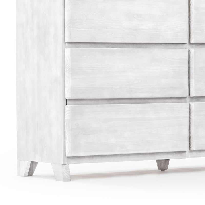 Close-up of a whitewashed wooden dresser lower corner with recessed drawer fronts and tapered mid-century style legs, modern farmhouse bedroom storage furniture