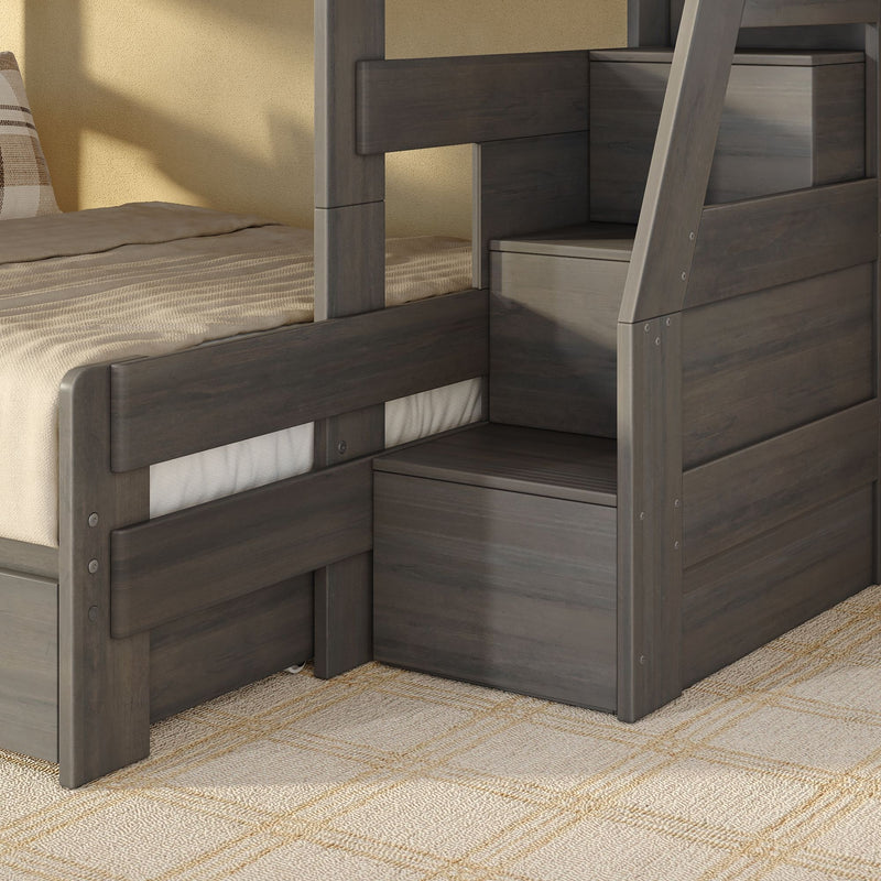 Gray wooden bunk bed with built-in storage stairs and drawers, beige bedding and plaid accent pillow in a modern kids' bedroom