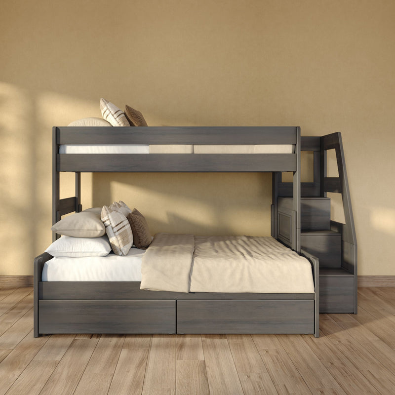 Gray wooden bunk bed with built-in staircase, neutral beige bedding and plaid accent pillows against a textured tan wall on hardwood flooring