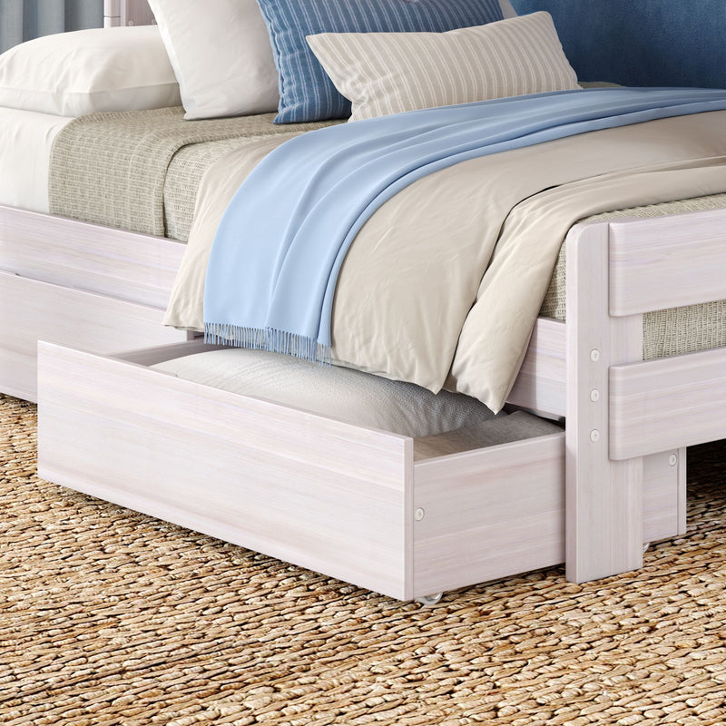 Close-up of light wood storage trundle bed with neutral bedding, pale blue throw blanket, striped accent pillows and woven jute rug