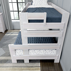 White wooden bunk bed with navy quilted bedding and polka dot sheets in a modern bedroom setting.