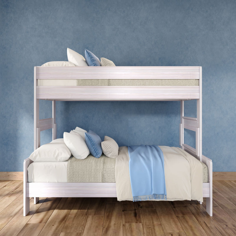 White wooden twin-over-full bunk bed with beige linens, blue throw blanket and striped accent pillows against a blue textured wall on hardwood floor