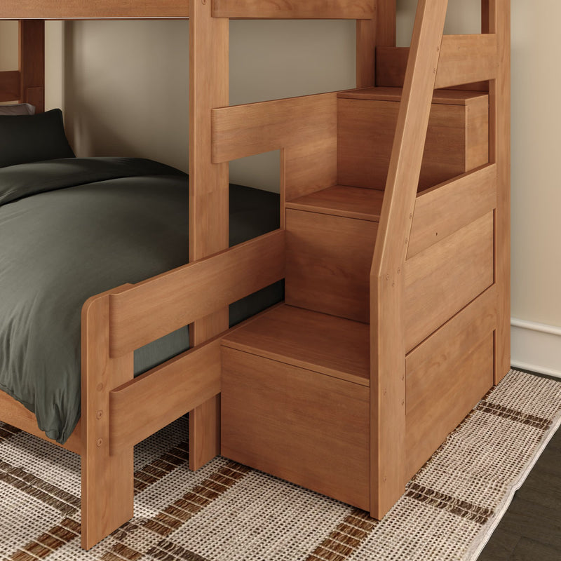 Solid wood twin-over-twin bunk bed with built-in storage stairs, natural wood finish, dark bedding and area rug in a space-saving kids' bedroom