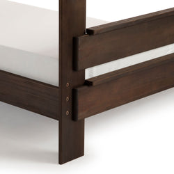 Close-up of wooden bed frame corner detail showing dark wood and white mattress for modern bedroom furniture design.