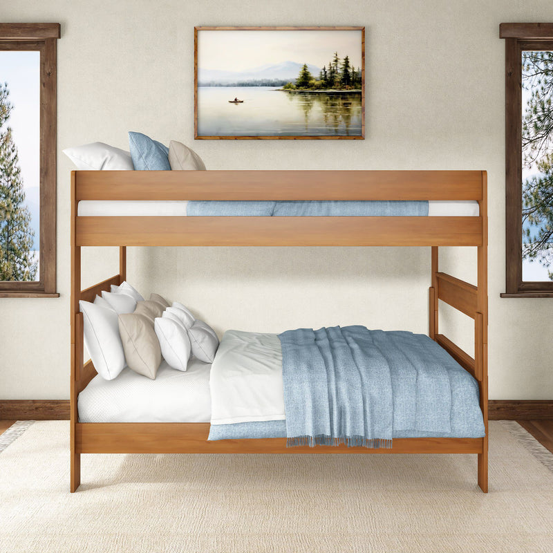 Contemporary solid wood bunk bed with blue bedding and layered pillows in a bright rustic bedroom featuring a framed lake painting and large windows