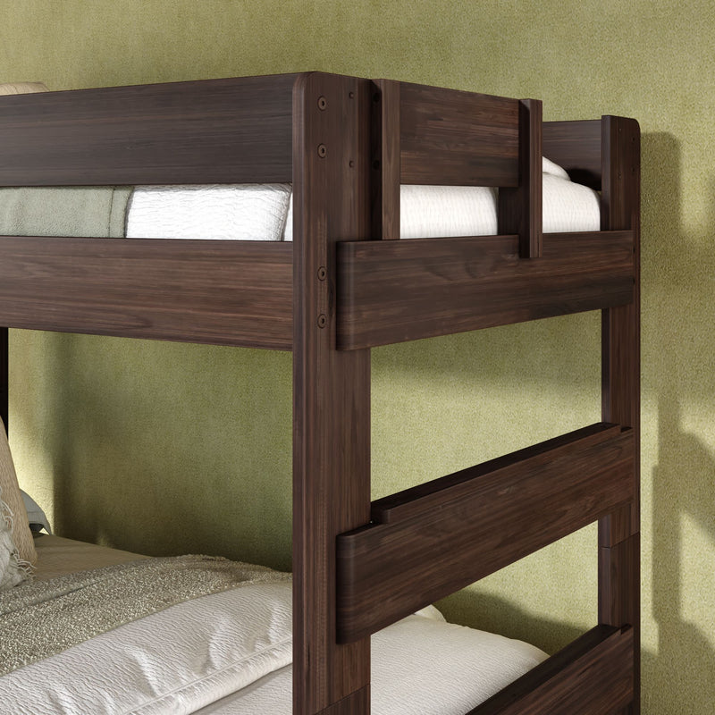 Close-up of a modern dark wood bunk bed frame with built-in guardrails and white bedding against a green textured wall, sturdy twin-over-twin design for kids' bedrooms.