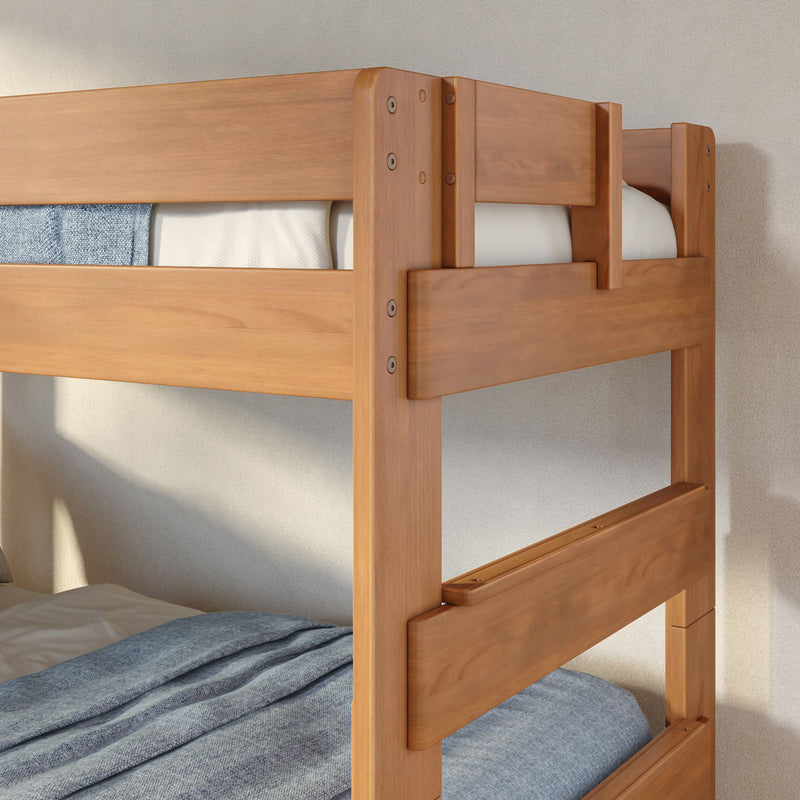 Solid wood bunk bed frame with protective safety rails and blue linen bedding in a bright modern bedroom
