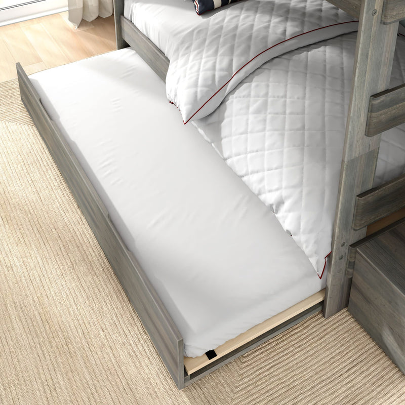 Gray wooden bunk bed with under-bed trundle mattress pulled out on beige rug — space-saving trundle bed and storage drawer
