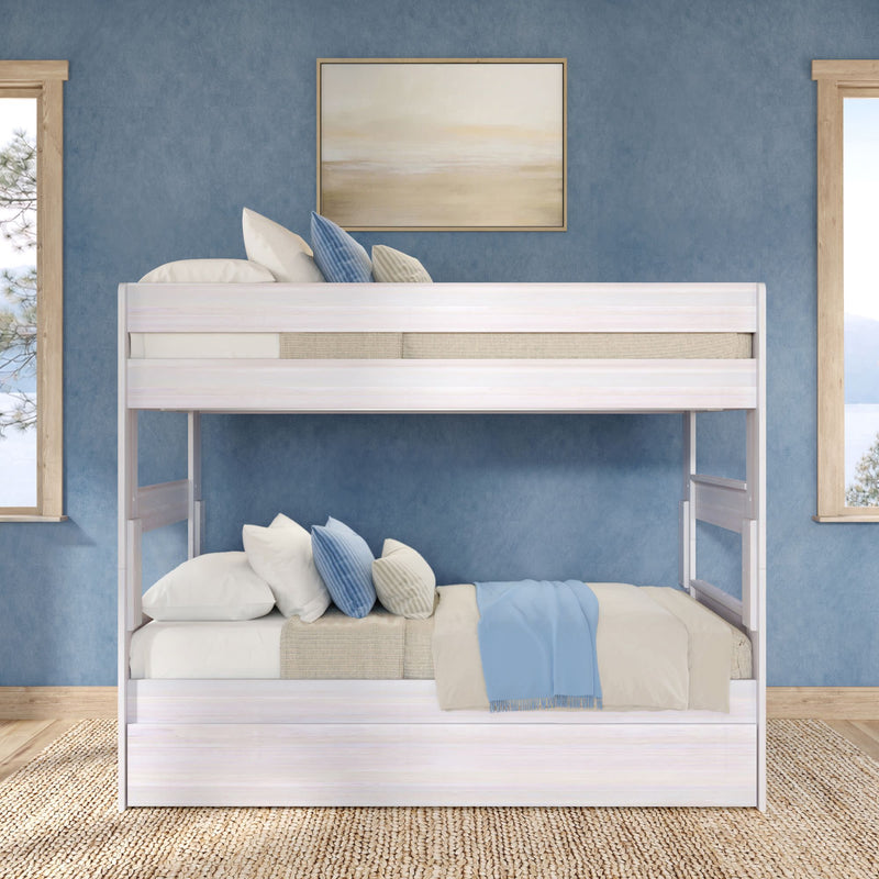 White wooden bunk bed in coastal-style blue bedroom with layered neutral bedding, blue and beige throw pillows, light-wood windows and natural jute rug