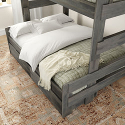 Dark wood bunk bed with white linens and a cozy blanket on a patterned rug in a modern bedroom.