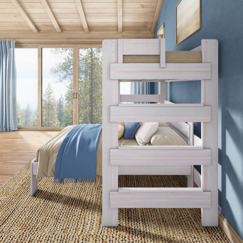 White wooden bunk bed in a cozy rustic bedroom with blue throw blanket, woven jute rug and large windows overlooking a pine forest view