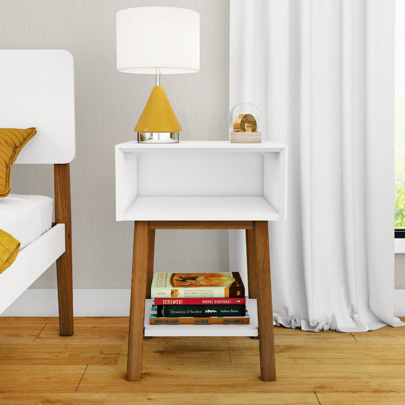 Modern bedroom with white nightstand, stack of books, yellow lamp, and cozy bed setup.