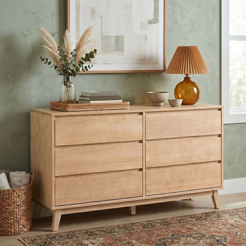 Mid-century modern natural wood dresser styled with amber glass lamp, pampas grass and eucalyptus vase, stacked books and ceramic bowls on rattan tray against sage green wall art, boho home decor