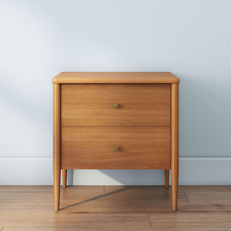 Mid-century modern light wood two-drawer bedside table with brass knobs on hardwood floor against pale blue wall