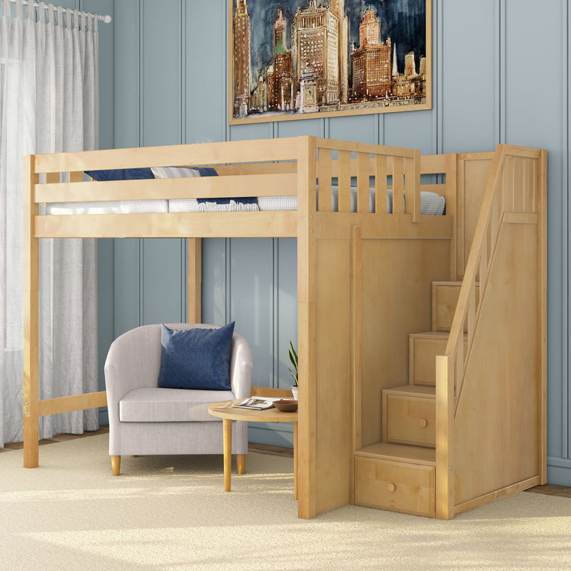 Light wood loft bed with staircase and built-in storage drawers above a cozy armchair reading nook with round side table and blue paneled wall