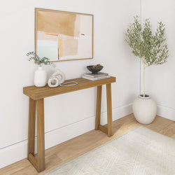 Contemporary entryway with wooden console table, abstract art, decorative vases, books, and an olive tree plant in a minimalist interior design.
