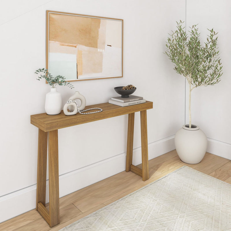 Contemporary entryway with wooden console table, abstract art, decorative vases, books, and an olive tree plant in a minimalist interior design.