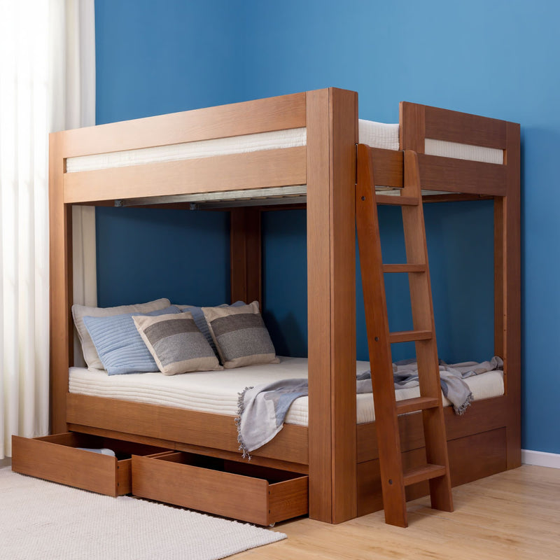 Modern solid wood bunk bed with ladder and under-bed storage drawers, styled with pillows and a throw against a blue bedroom wall