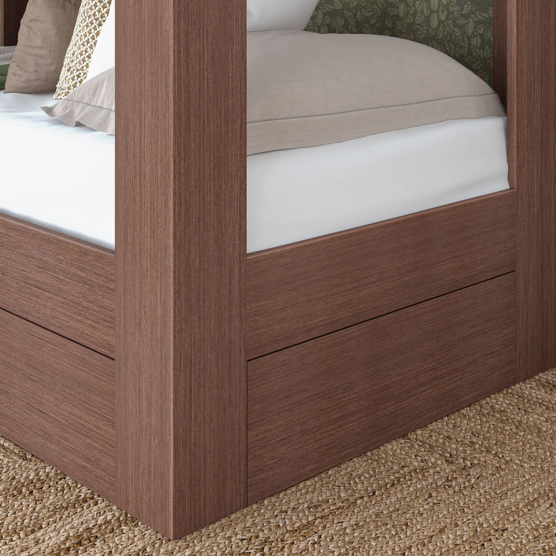 Close-up of walnut-finish four-poster platform bed corner with beige bedding, low-profile mattress and integrated storage panel on woven jute rug in a modern farmhouse bedroom