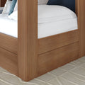 Modern oak platform bed frame corner with built-in under-bed storage drawers, crisp white bedding and textured beige rug, contemporary bedroom furniture