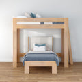 Modern light wood loft bunk bed (twin-over-twin) with lower single bed, blue patterned bedding and pillows in a minimalist Scandinavian kids bedroom, space-saving design