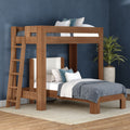 Solid wood loft bunk bed with built-in ladder and gray-blue bedding in a modern bedroom with navy accent wall and potted plant