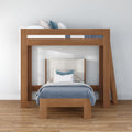 Modern solid wood loft bunk bed with lower twin bed, blue patterned duvet and decorative pillows in a minimalist bedroom with hardwood floors