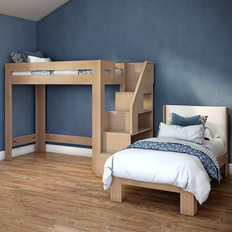 Wooden loft bed with built-in storage stairs next to a twin bed in a modern kids' bedroom with blue accent wall, hardwood floor and blue-white bedding