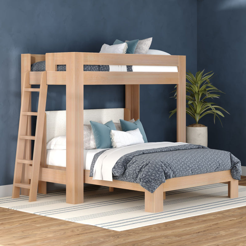 Modern light-wood twin-over-full bunk bed with ladder, blue-gray bedding and decorative pillows in a navy-accent bedroom with striped rug and potted plant