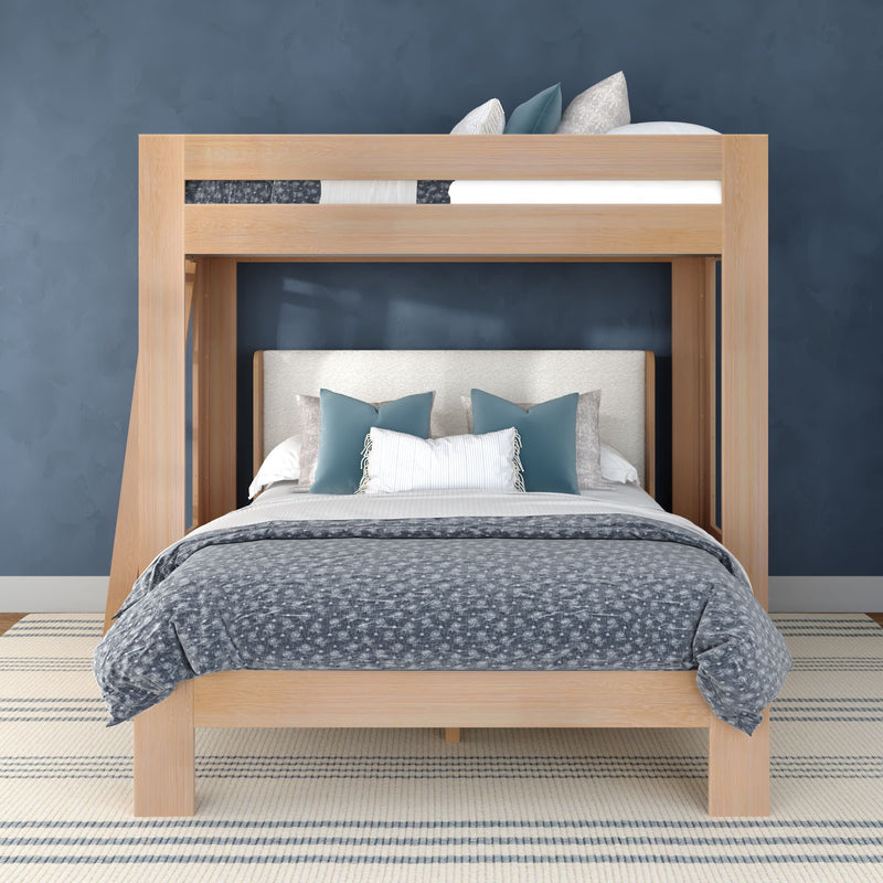 Modern light-wood loft bunk bed with upholstered headboard, gray patterned duvet and teal accent pillows against a navy blue wall and striped rug