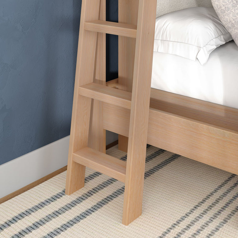 Light oak wooden ladder attached to a loft bunk bed beside a textured blue wall with white bedding and a striped beige rug in a modern bedroom