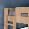 Close-up of light oak wooden bunk bed ladder and guardrail with gray patterned bedding against a navy blue textured wall