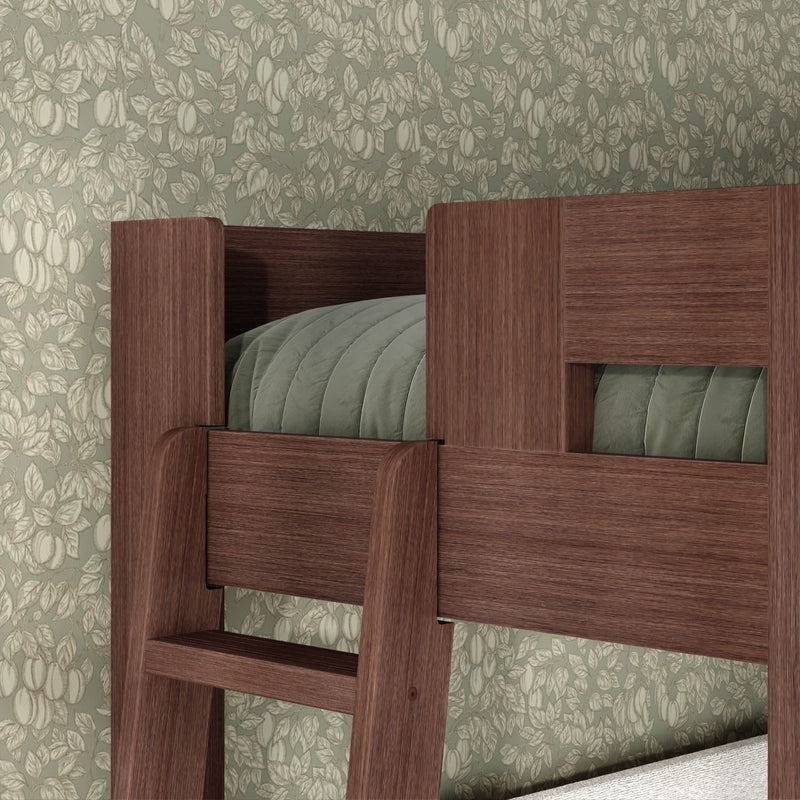 Close-up of dark wood bunk bed ladder and upper guardrail with sage-green quilted bedding against vintage floral wallpaper