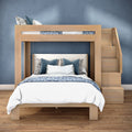 Modern light-wood twin-over-full bunk bed with built-in stairs in blue bedroom, hardwood floor, white and navy patterned bedding and decorative pillows