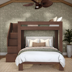 Modern wooden loft bunk bed with staircase over queen bed, neutral pillows and linens, green floral wallpaper, rattan ceiling fan and potted plant.