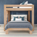 Light-wood loft bunk bed with full lower bed and twin upper bed, blue-gray quilted bedding, teal decorative pillows, navy accent wall and striped rug