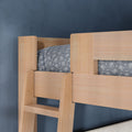 Close-up of natural wood bunk bed ladder and guardrail with gray floral bedding against a navy blue bedroom wall