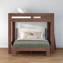 Modern wooden loft bunk bed with queen-size lower bed and twin upper bunk, green quilted comforter and beige decorative pillows on hardwood floor