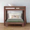 Modern wooden loft bunk bed with queen-size lower bed and twin upper bunk, green quilted comforter and beige decorative pillows on hardwood floor
