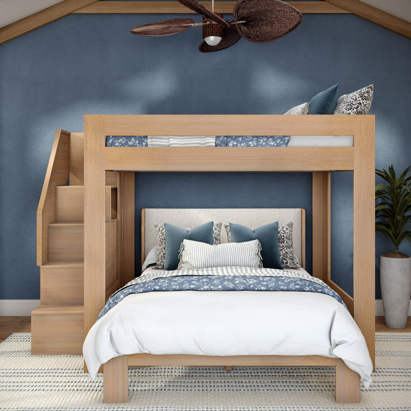 Light wood twin-over-full bunk bed with staircase storage, blue floral bedding and navy accent wall in a modern coastal bedroom