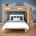Modern wooden loft bunk bed with built-in stairs, full-size lower bed and twin upper, blue patterned bedding on hardwood floor