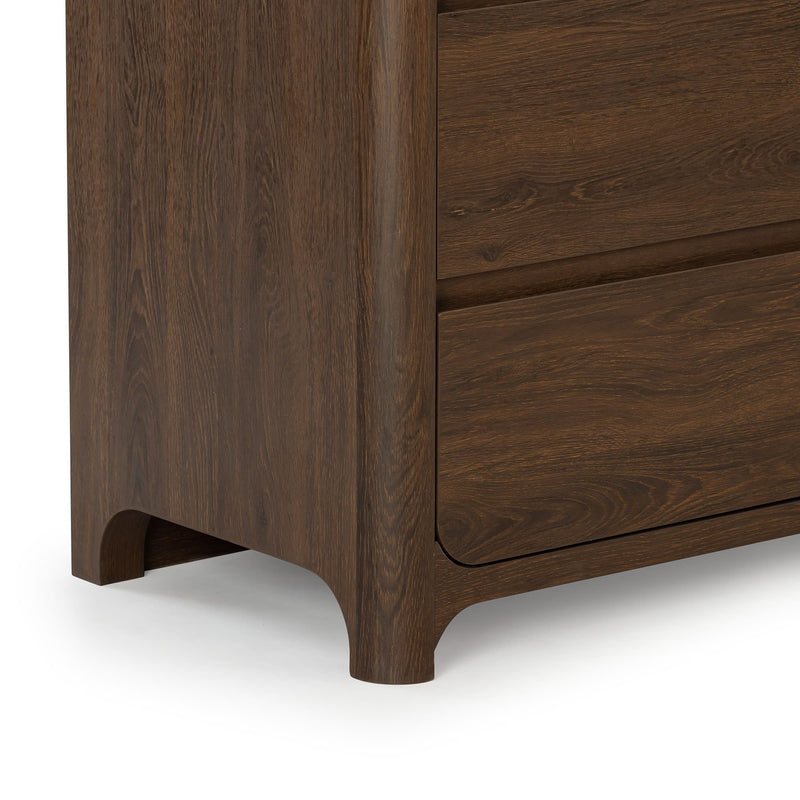 Close-up of dark brown oak wood-grain dresser corner with arched legs and recessed drawer front, modern mid-century bedroom furniture