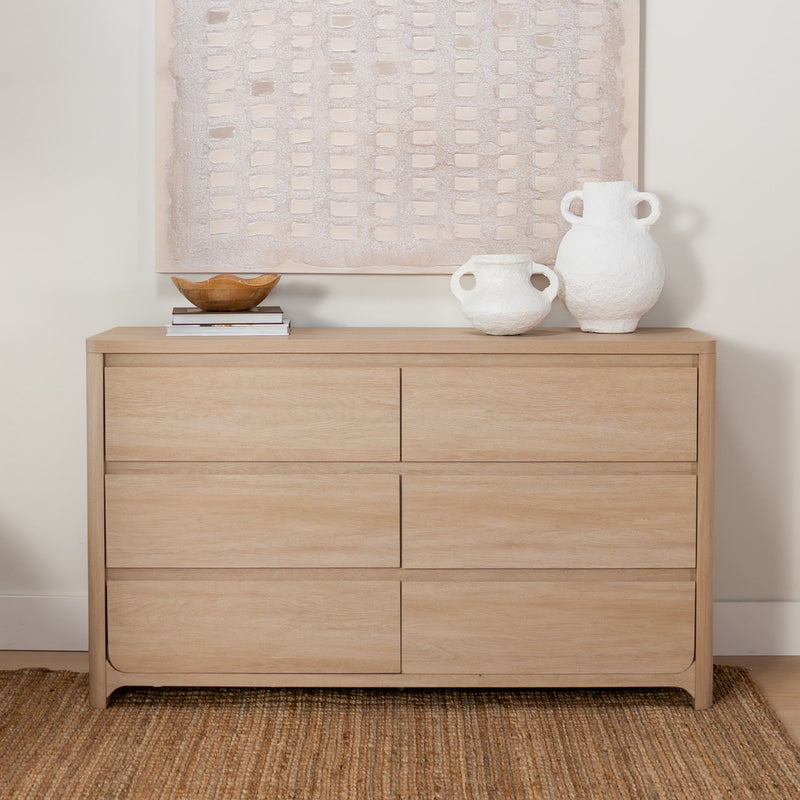 Light oak minimalist dresser topped with textured neutral abstract wall art, white textured ceramic vases, wooden bowl on books and natural jute rug — Scandinavian modern bedroom decor