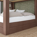 Modern walnut four-poster platform bed with built-in storage base, white mattress and beige pillows against a green floral wallpaper accent wall over a jute rug